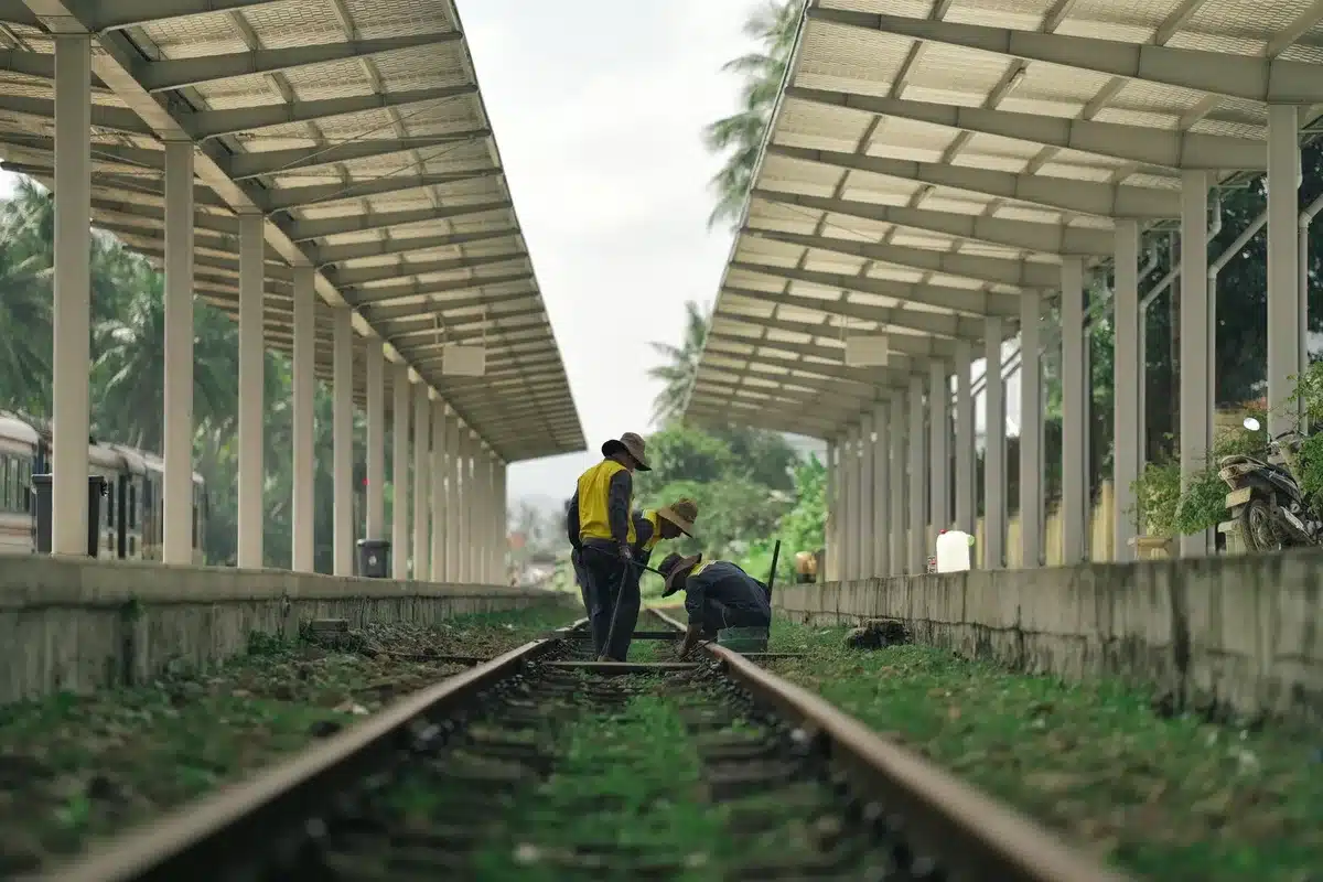 Trabajadores anónimos realizando labores de mantenimiento urgente en vías de ferrocarril con equipamiento de seguridad
