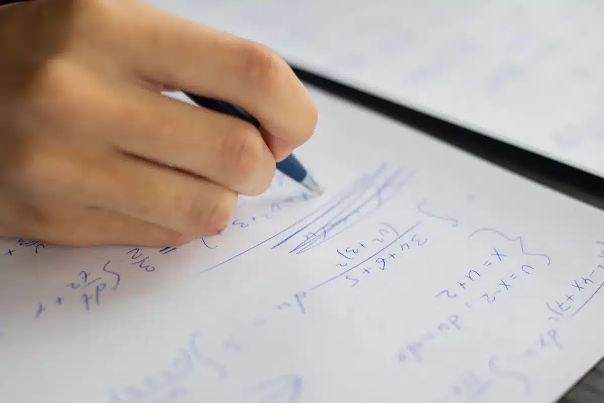 Alumnos trabajando en equipos resolviendo problemas matemáticos con material manipulativo en el aula.