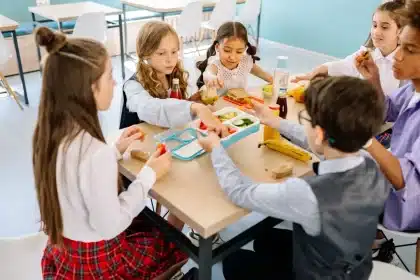 Profesor y estudiante compartiendo mesa en comedor escolar, en conversación atenta