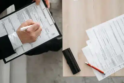 Manos firmando un contrato laboral en una mesa de oficina con documentos y bolígrafo