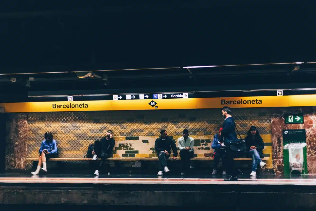 Pasajeros en una estaci&oacute;n de metro con se&ntilde;alizaci&oacute;n de l&iacute;neas de transporte