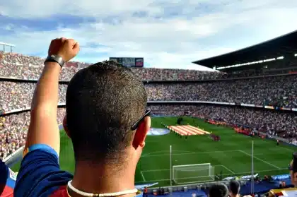 Multitud de personas reunidas en una plaza pública frente a una pantalla gigante para ver un evento deportivo