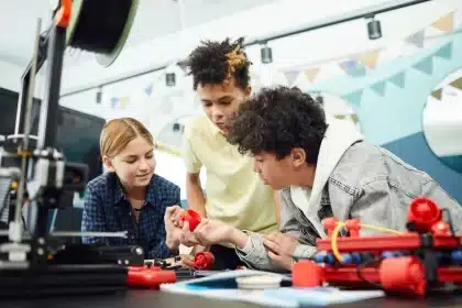 Manos trabajando en un prototipo en un taller de formación profesional con herramientas y documentos técnicos