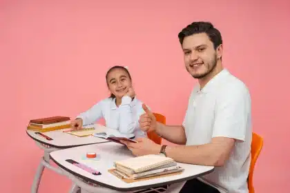 Estudiante concentrado en su escritorio con libros y cuadernos, en un aula de clase
