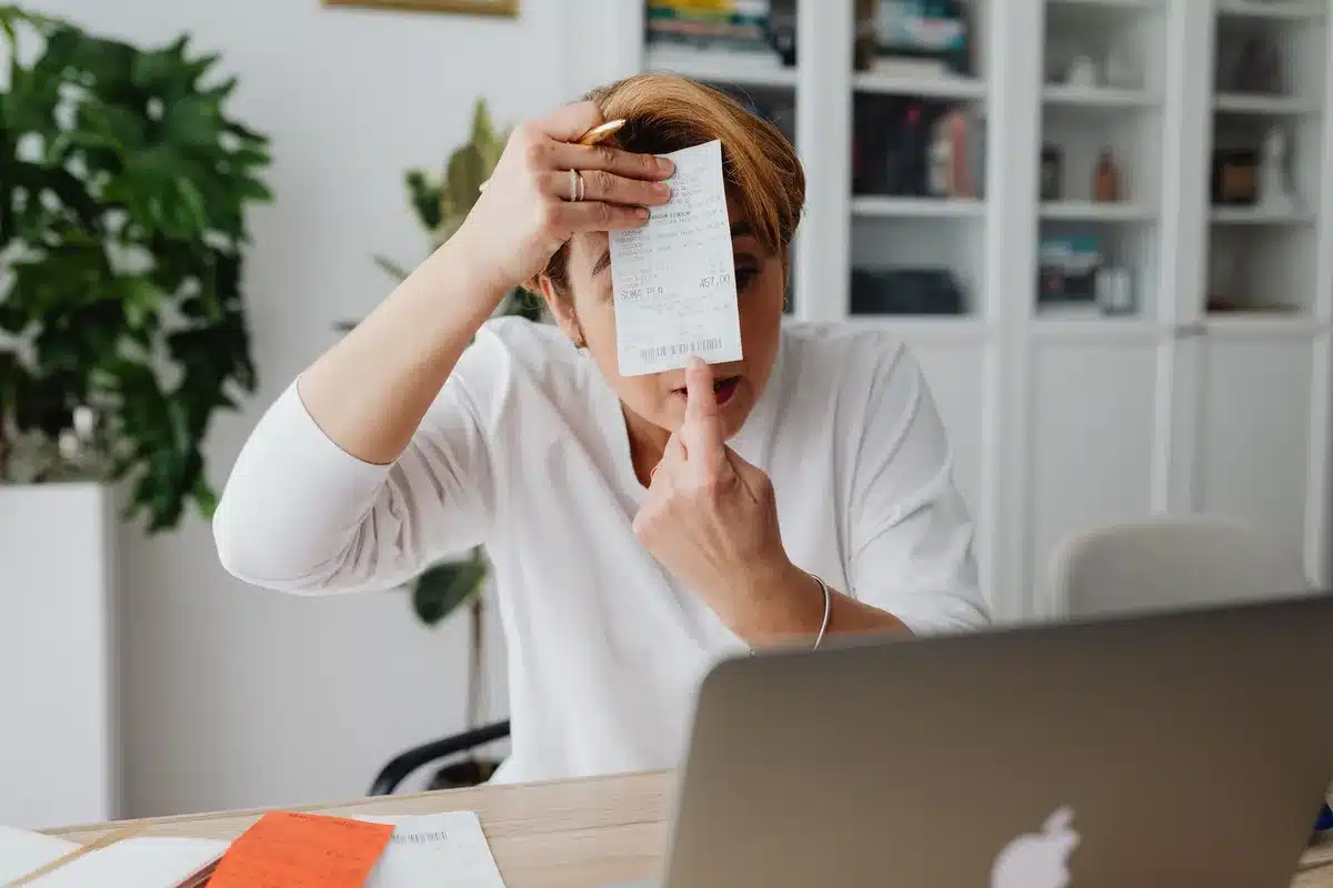 Autónomo trabajando en su escritorio con facturas y software de facturación en pantalla
