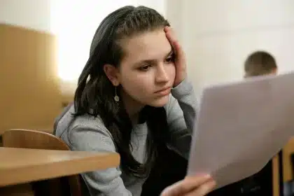 Estudiante estresado durante la preparación de un examen, rodeado de libros y apuntes.