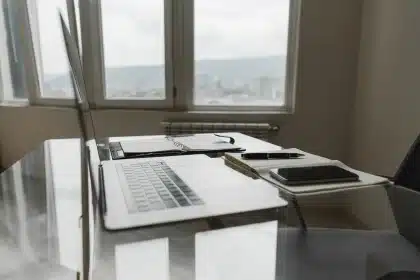 Manos sosteniendo documentos de factura digital junto a un escritorio con ordenador de fondo