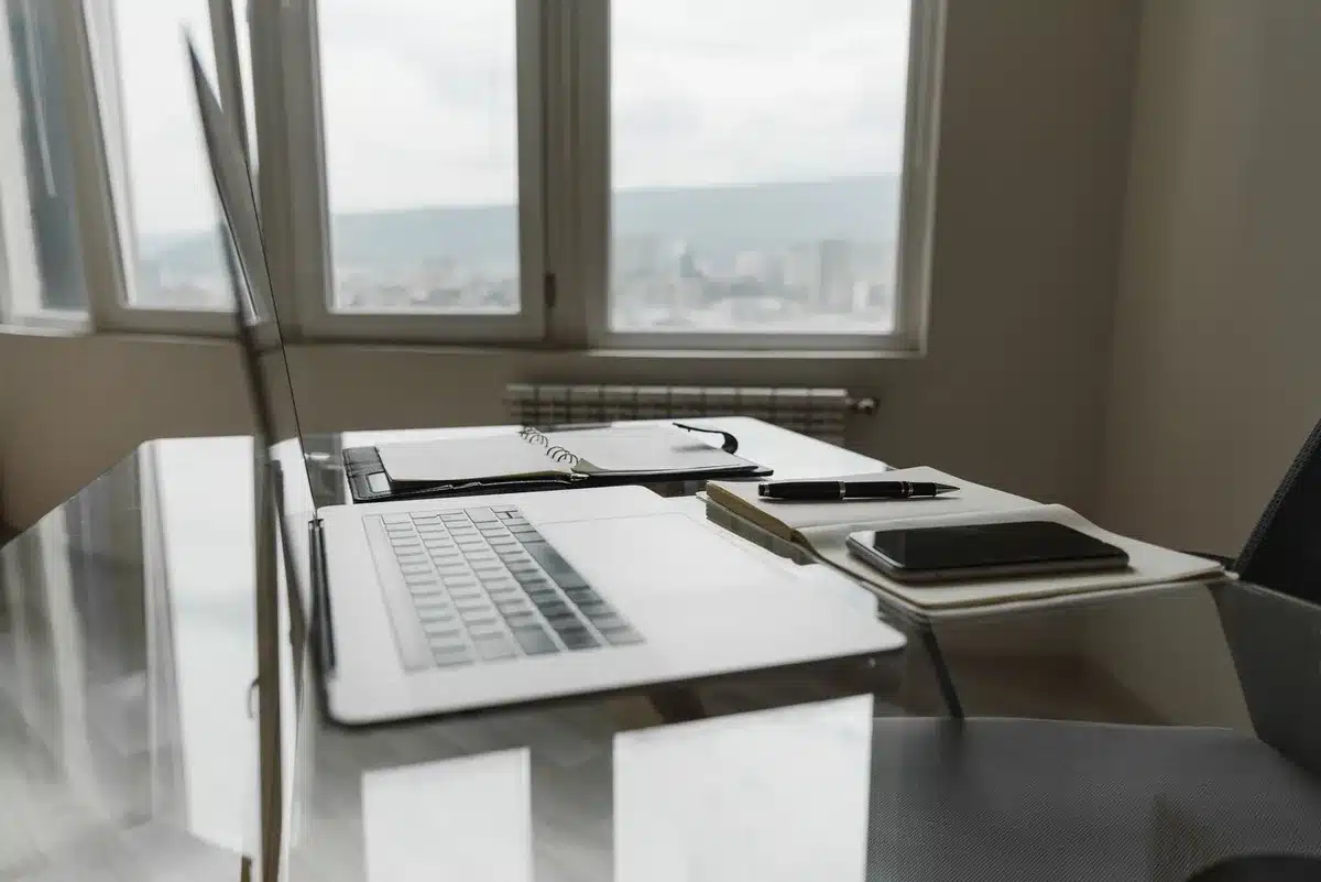 Manos sosteniendo documentos de factura digital junto a un escritorio con ordenador de fondo