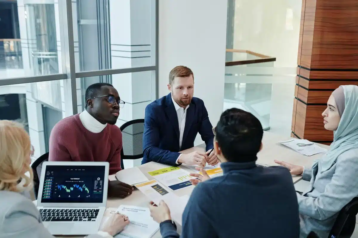 Equipo diverso colaborando en reunión de trabajo alrededor de una mesa