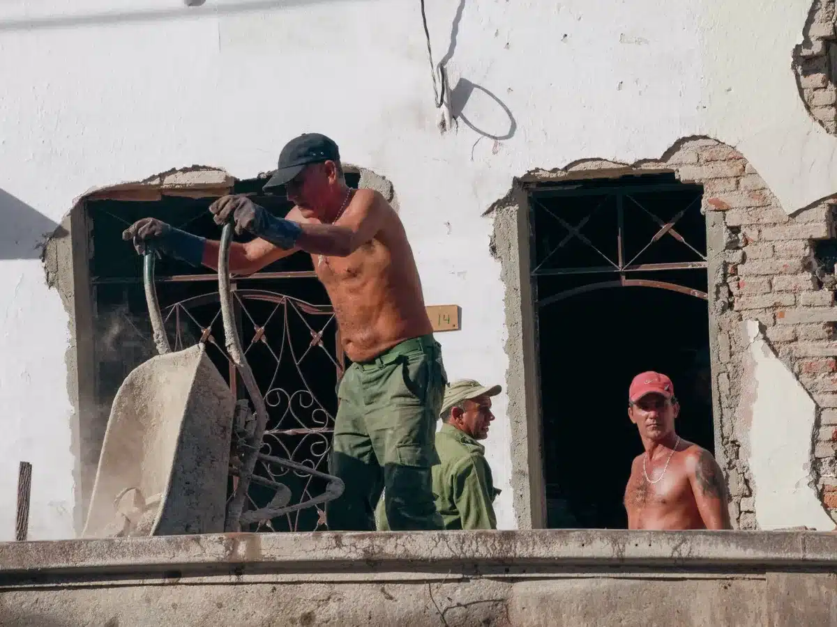 Trabajadores en exterior bajo calor intenso con bruma térmica visible en el pavimento