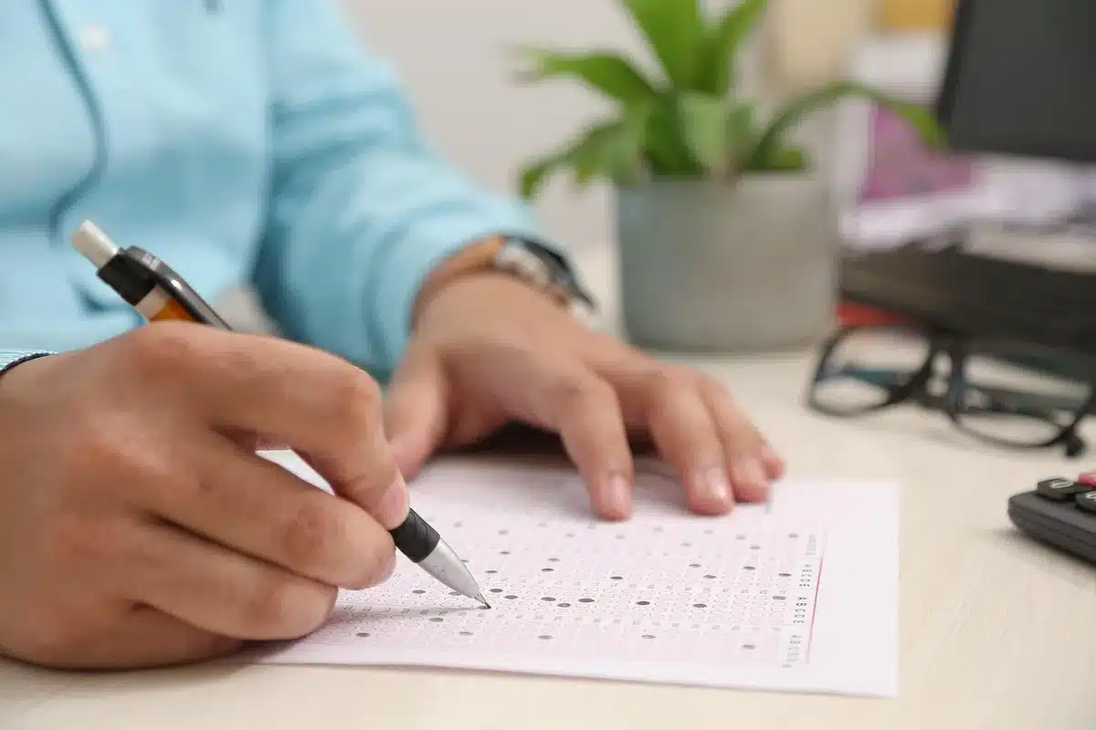 Persona completando formulario de solicitud con documentos administrativos sobre la mesa.