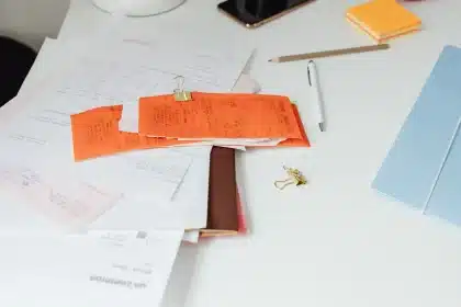 Manos corrigiendo errores en una factura impresa con bolígrafo rojo sobre escritorio
