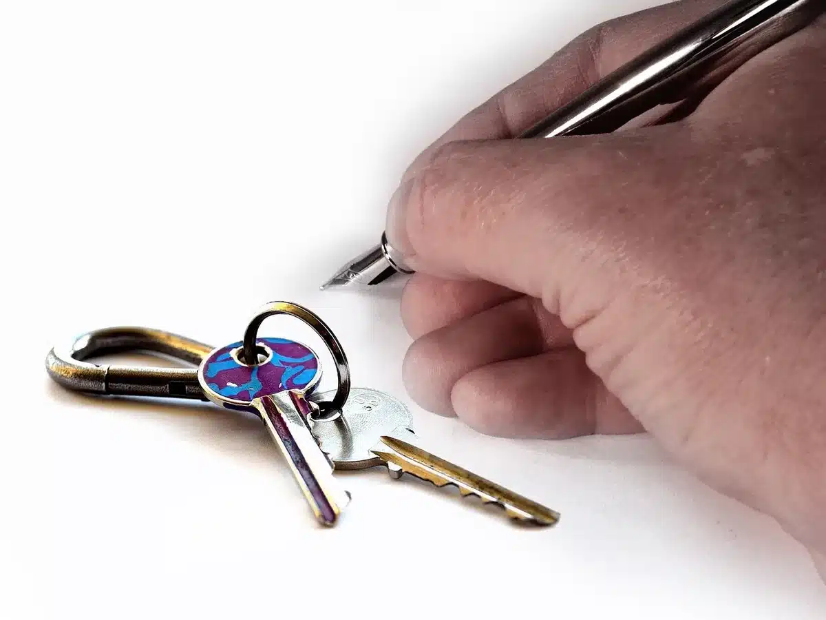 Llave y contrato de compraventa sobre una mesa frente a una ventana con ciudad