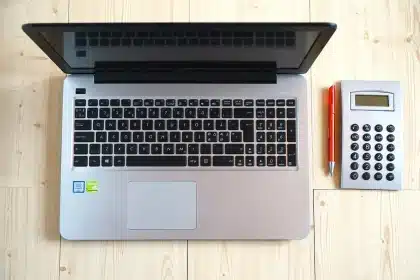 Manos anónimas con factura y calculadora sobre una mesa de trabajo