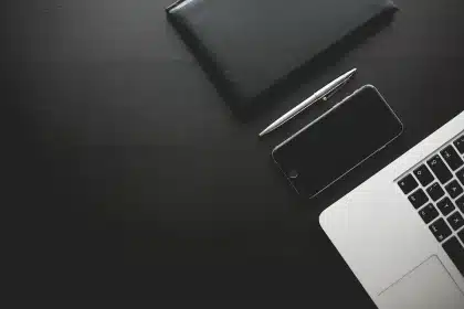 Manos sosteniendo cuadernos de periodismo y un teléfono sobre una mesa de oficina