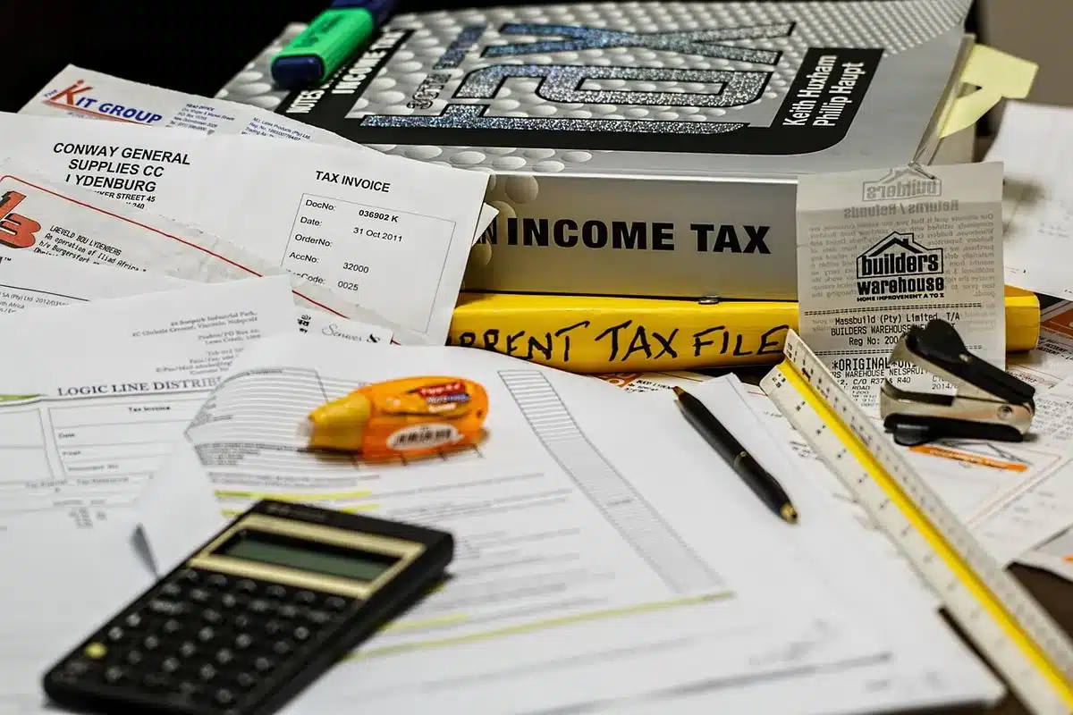 Manos anónimas calculando facturas y cuotas en una mesa de oficina en casa