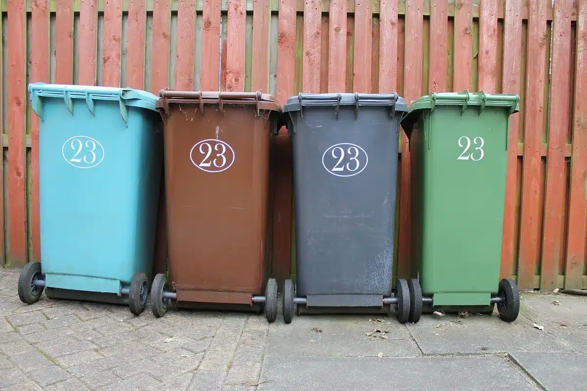 Manos clasificando residuos en contenedores separados de reciclaje