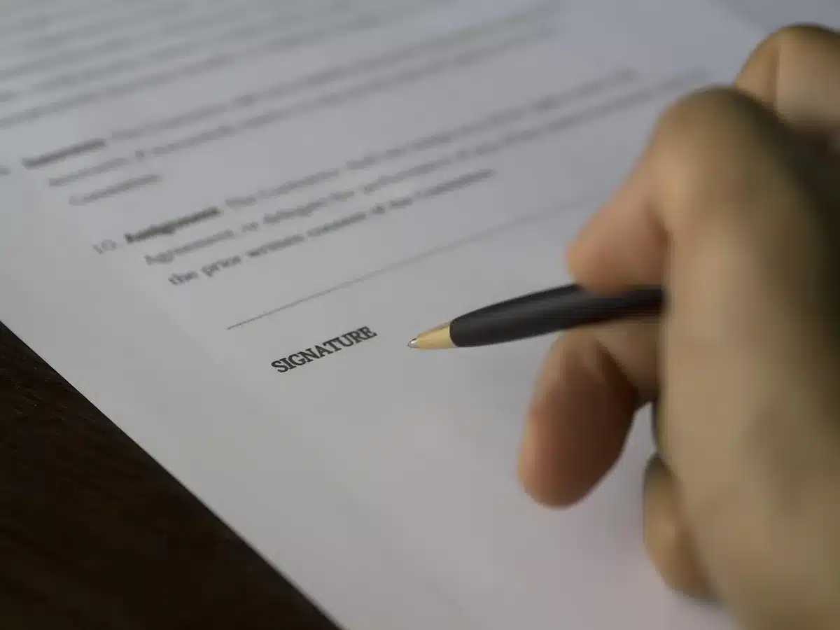 Manos anónimas de cuidador y persona mayor sobre documentos en casa