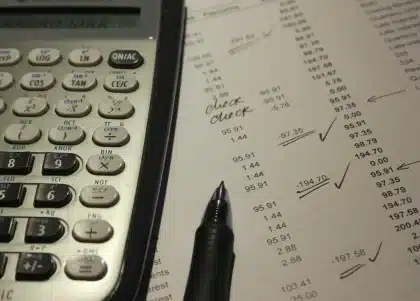 Persona en un escritorio con documentos de Seguridad Social, calculadora y ordenador portátil