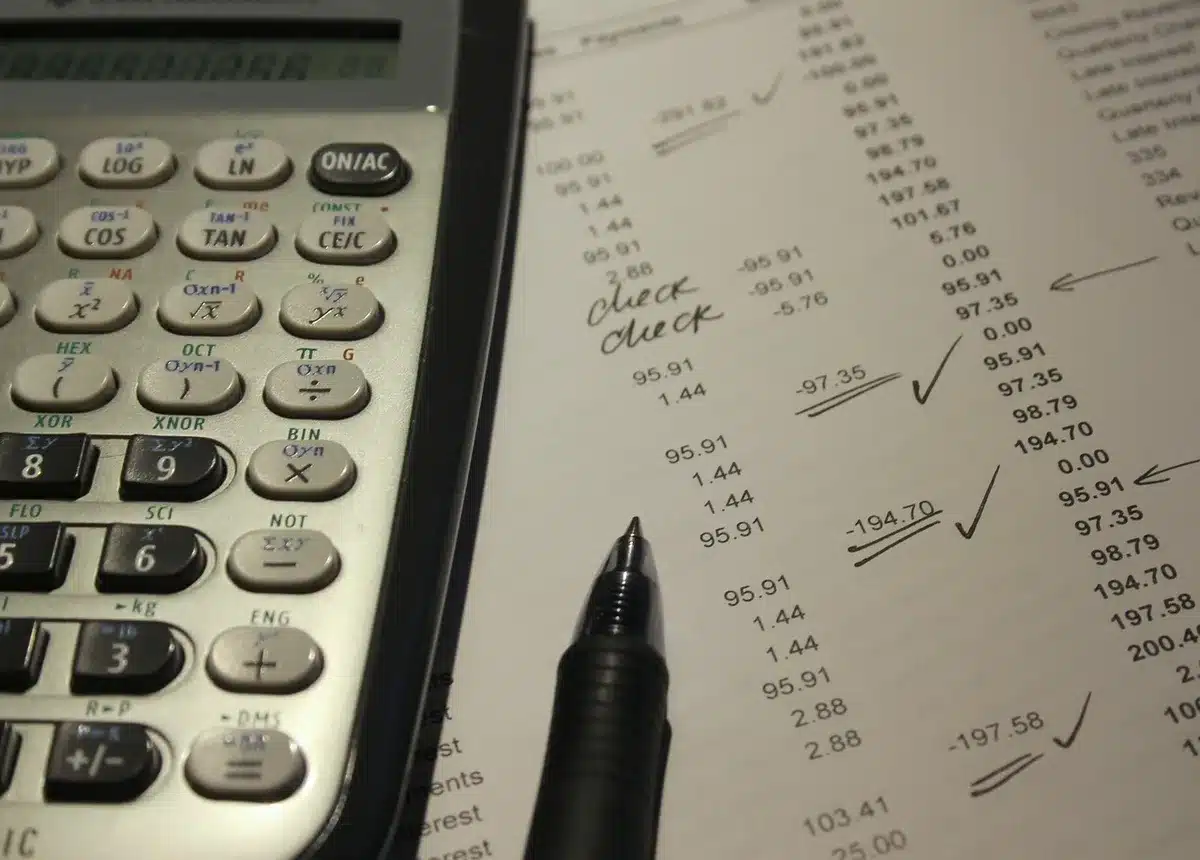 Persona en un escritorio con documentos de Seguridad Social, calculadora y ordenador portátil
