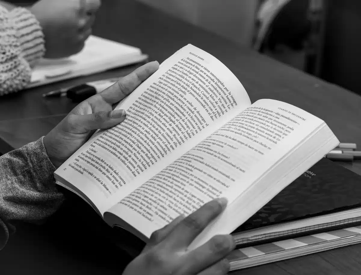 Manos anónimas sobre libros y un kit STEAM en un aula luminosa
