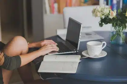 Manos anónimas llenando documentos fiscales junto a un portátil y un calendario