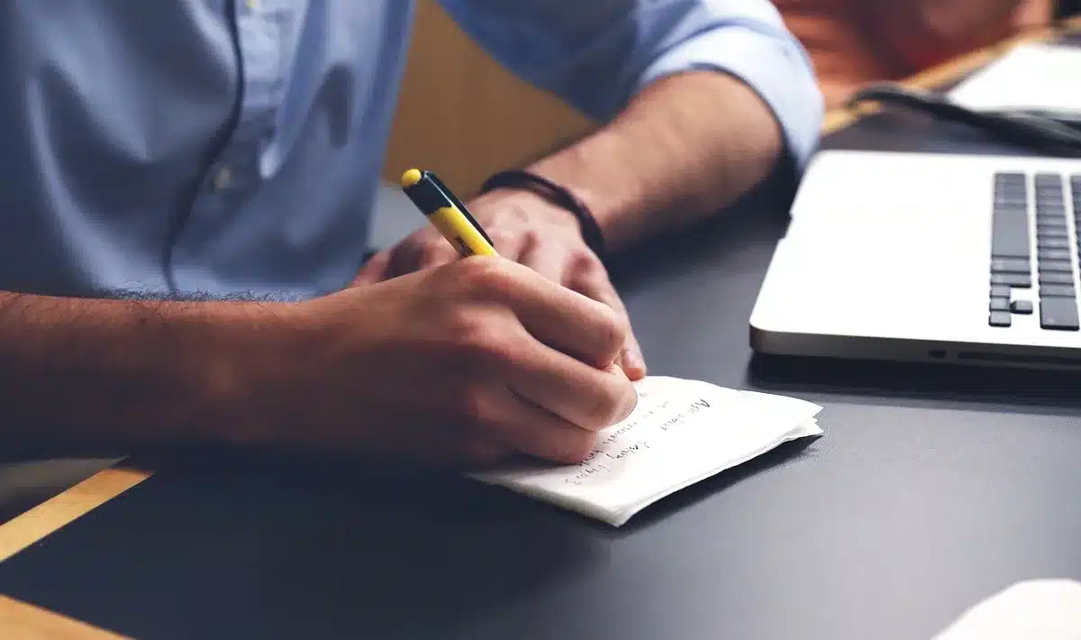 Manos de contable anotando fechas en facturas junto a un calendario en un escritorio