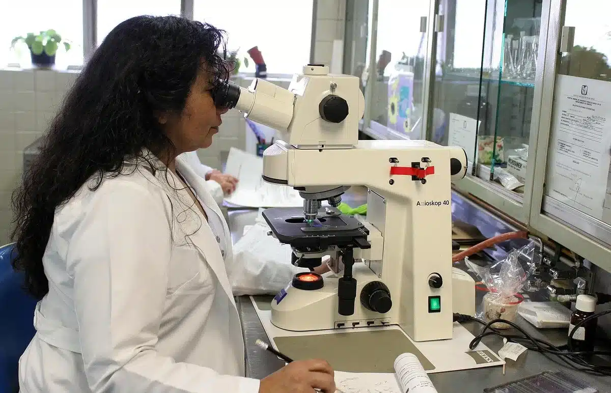 Manos con guantes manipulando tubos de ensayo y equipos de laboratorio clínico