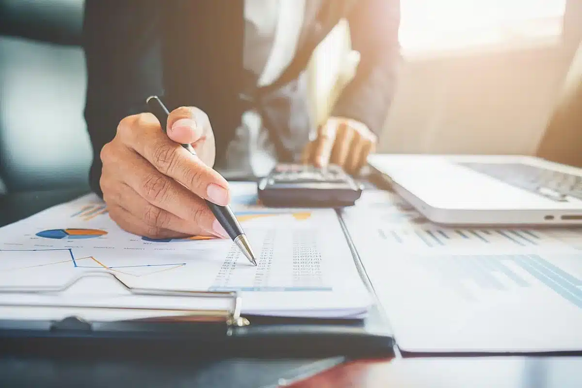 Persona revisando documentos y apuntes financieros en un escritorio